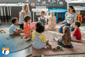 children sitting in circle on floor with two teachers